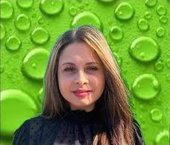 Female employee in front of green background. 
