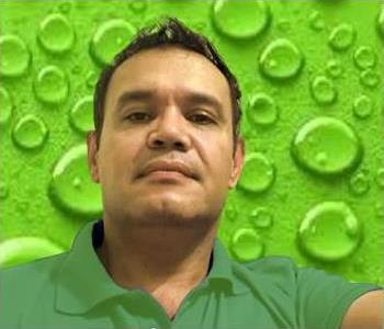 Male employee in green shirt in front of green background. 